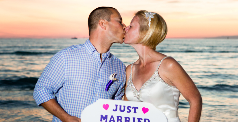 Couple holding Just Married sign as they kiss